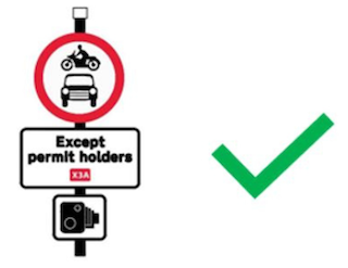 A red, circular 'No motor vehicles sign' with an 'Except permit holders sign' underneath. There's a green tick next to the signs.