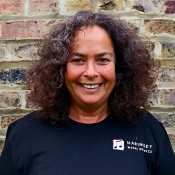 Woman standing in front of brick wall wearing Haringey Music Service t-shirt.