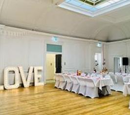 The ceremony room at Green Rooms, with tables and chairs and a sign saying 'LOVE"