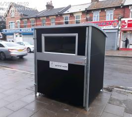 Large black box communal bin on the pavement of a high street.