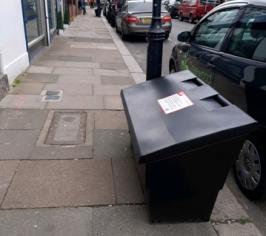 A low black box with slanted lid on the pavement of a Haringey street.